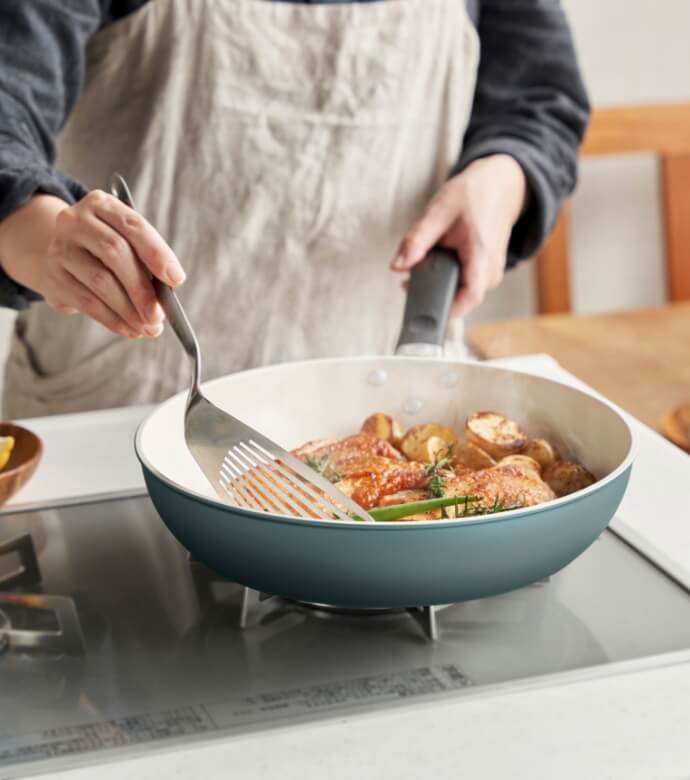 京セラのセラミックフライパンを使って、金属製のヘラで調理中の食材を炒めている様子